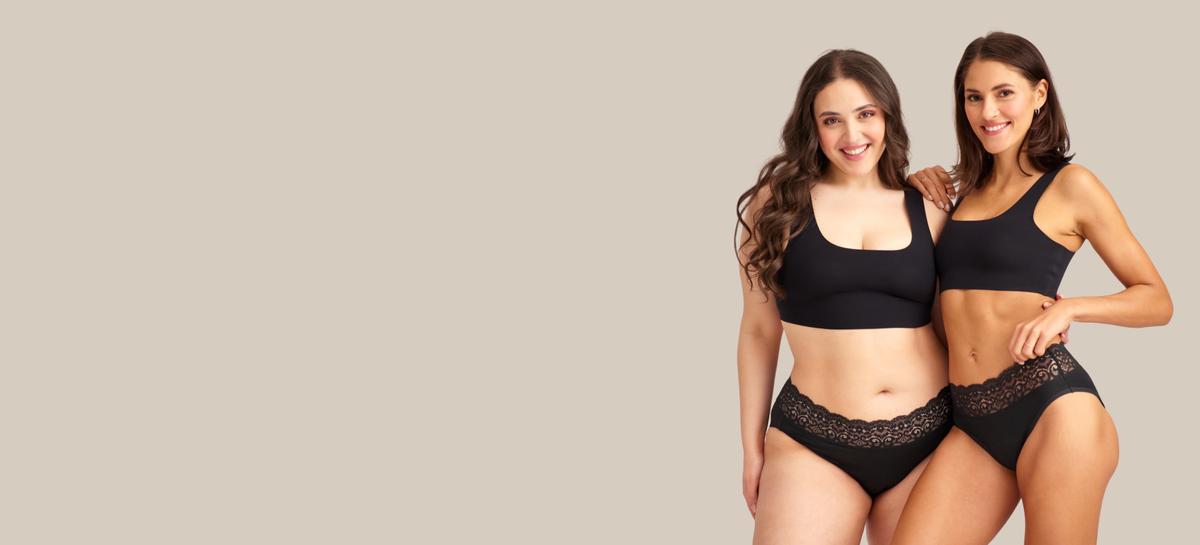 Zwei Models präsentieren ooia Periodenunterwäsche all-you-need Bra Top und Slip Extra Strong in schwarz. Frontal und Stehend.