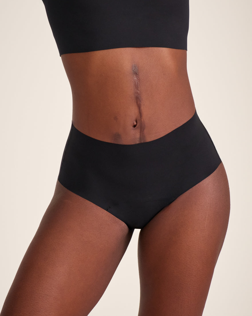 Modell trägt ooia Highwaist Seamless in Schwarz – nahtlose Periodenunterwäsche mit hohem Bund.