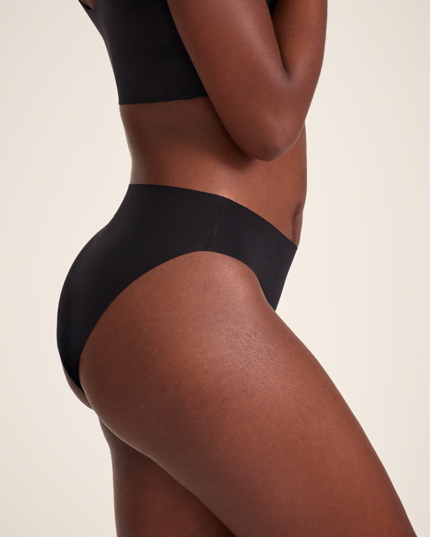 Modell trägt ooia Slip Seamless in Schwarz – nahtlose Periodenunterwäsche im klassischen Schnitt.