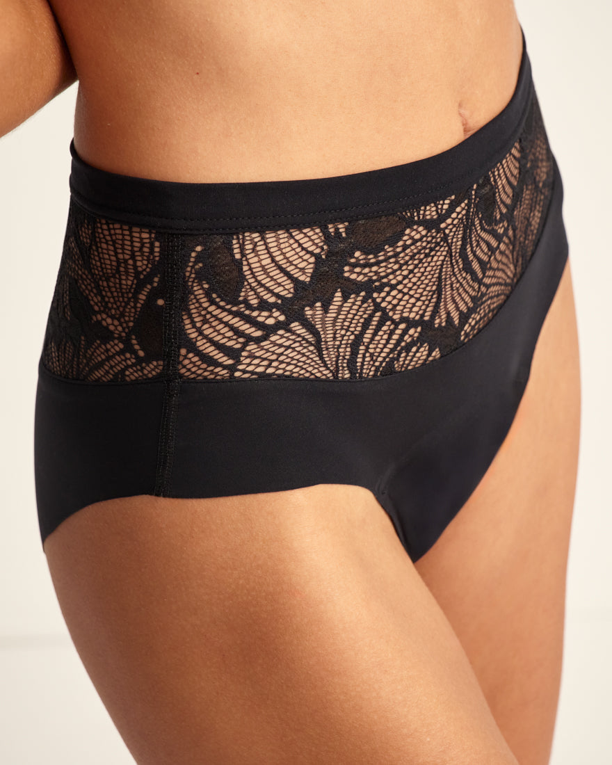 Modell trägt Periodenunterwäsche Highwaist Seamless Lace extra stark in schwarz mit nahtlosem Design mit breiter Spitze am Bund.
seitlich, detail