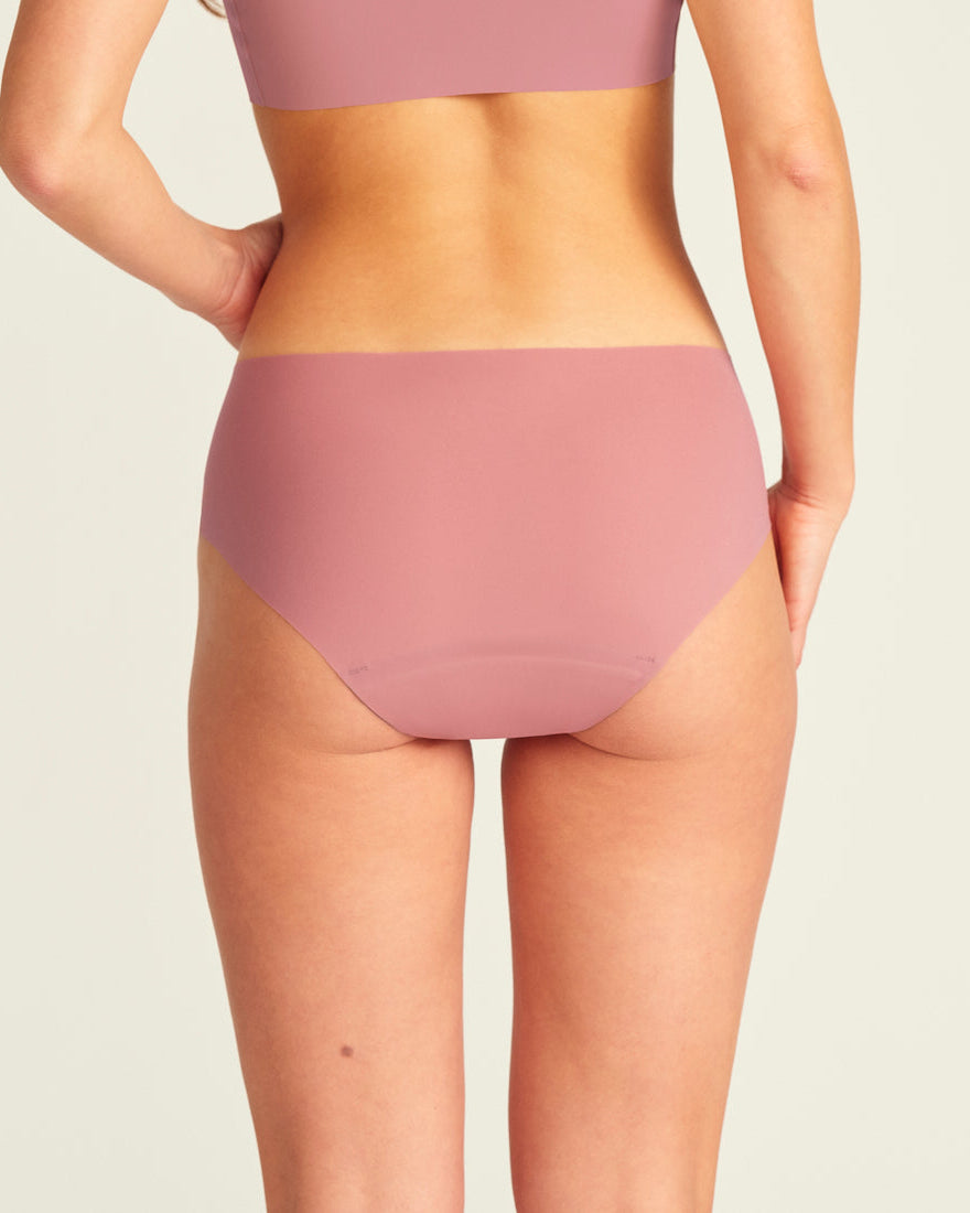 Modell trägt nahtlose ooia Periodenunterwäsche Hipster Seamless Extra Strong in dusky pink. Rückansicht.