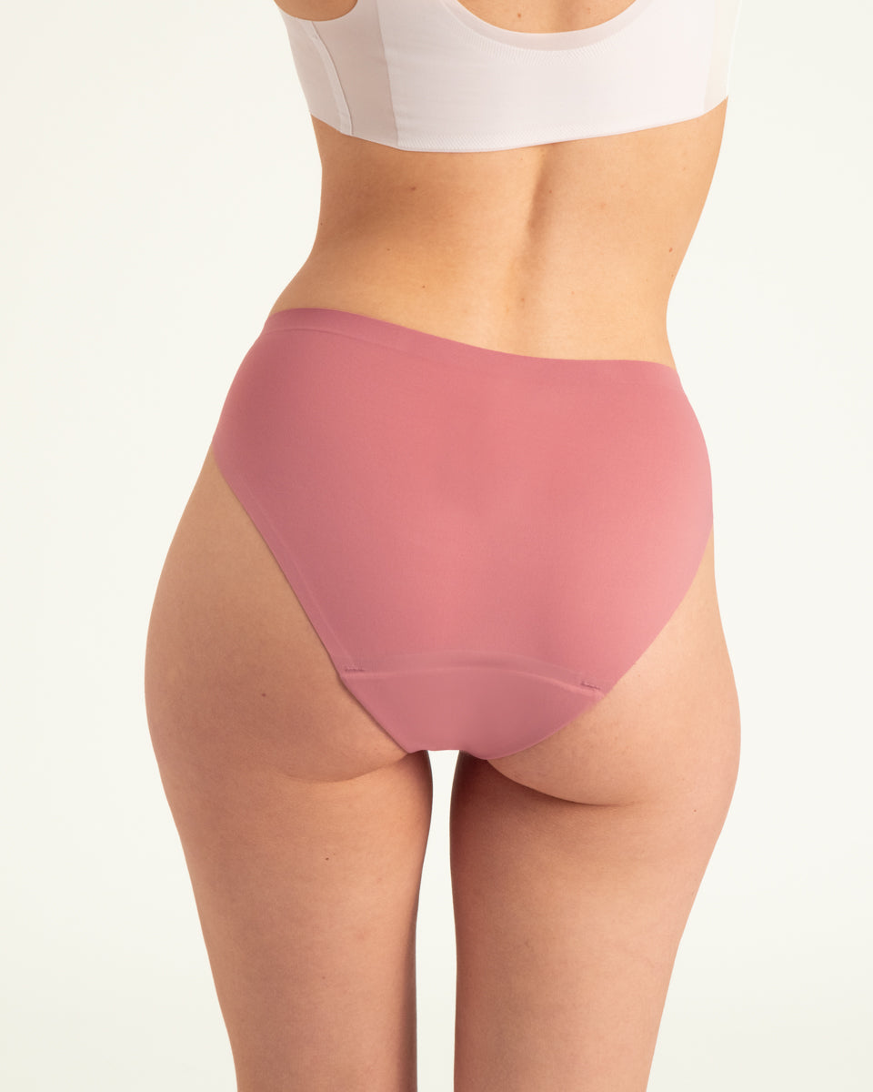 Modell trägt ooia Slip Seamless in Dusky Pink – nahtlose Periodenunterwäsche im klassischen Schnitt. Rückansicht.