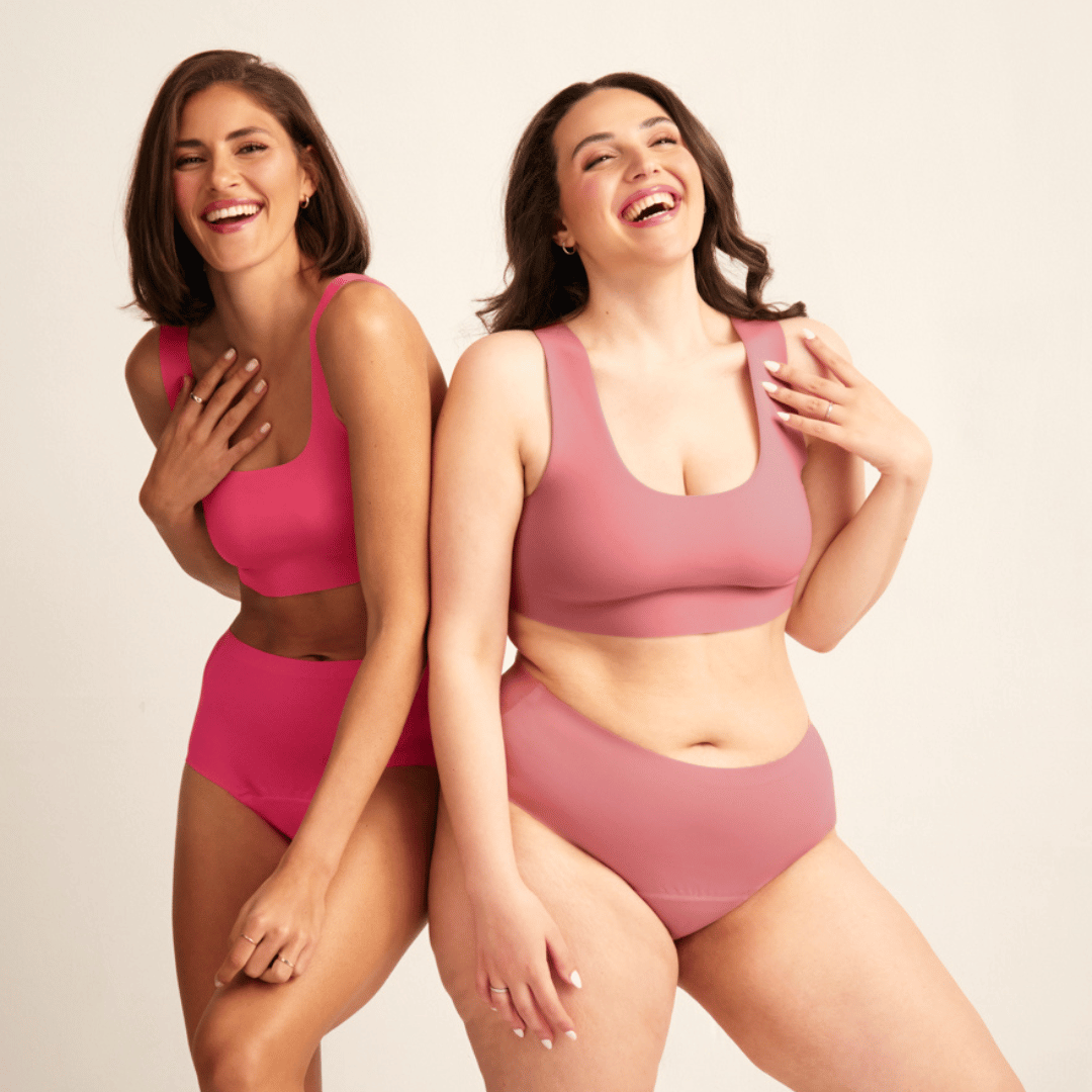 Zwei Models lachen zusammen in nahtloser Menstruations in den Farben hot pink und dusky pink