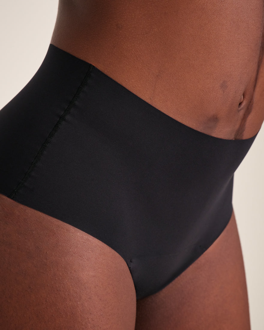 Modell trägt ooia Highwaist Seamless in Schwarz – nahtlose Periodenunterwäsche mit hohem Bund.