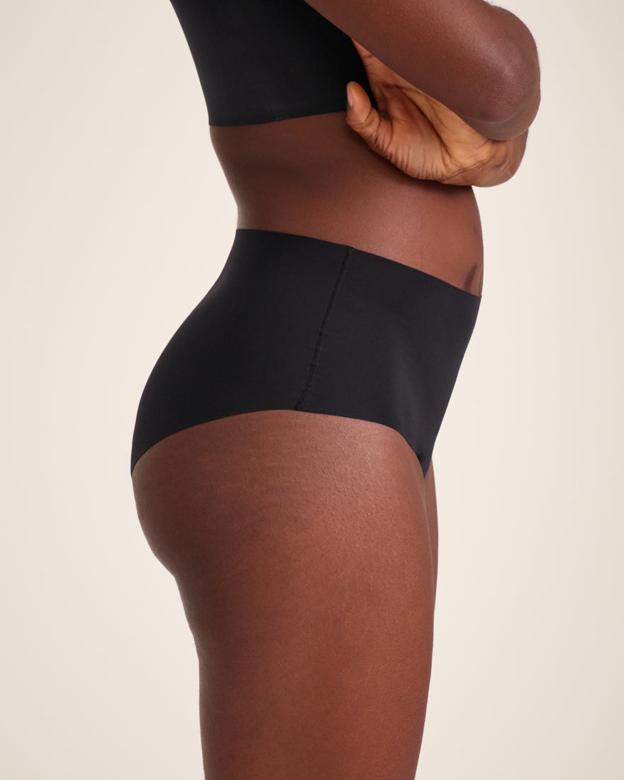Modell trägt ooia Highwaist Seamless in Schwarz – nahtlose Periodenunterwäsche mit hohem Bund.