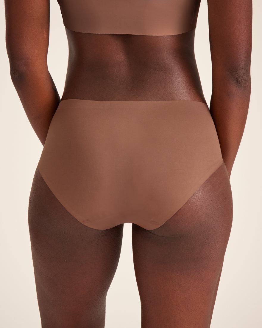 Modell trägt ooia Hipster Seamless in Braun – nahtlose Periodenunterwäsche. Rückansicht.