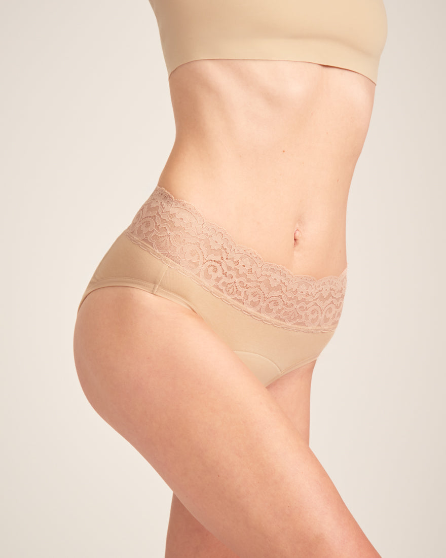 Modell trägt ooia Slip in Beige - Periodenunterwäsche mit breitem Spitzenbund im klassischen Schnitt.