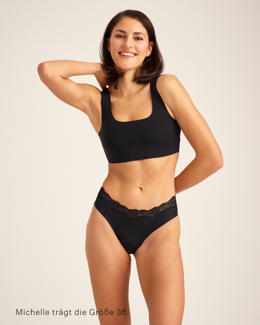 Modell trägt nahtlosen ooia Periodenunterwäsche Slip Seamless Lace Extra Strong in schwarz